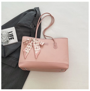 Pink woven tote bag featuring a decorative houndstooth ribbon bow and metal feet