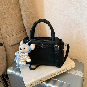 Retro black leather tote bag with teddy bear charm on vintage suitcase and blazer background