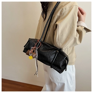 Shoulder bag detail showing black wrinkled patent leather and stylish hanging accessories