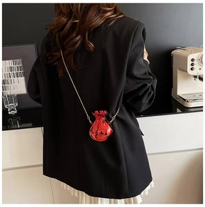 Close-up of a metallic red fortune bag mini bag with gold chain strap on a black blazer