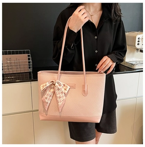 Detail of pink woven tote bag with houndstooth scarf bow and slim leather shoulder straps