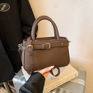 Retro dark brown tote bag with pebble leather texture and shoulder strap on silver suitcase