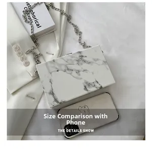 White marble pattern box clutch with silver chain compared to a smartphone for size