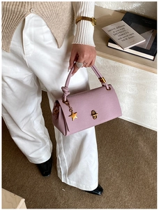 Detail of lavender litchi leather handbag with gold star charm and twist-lock closure
