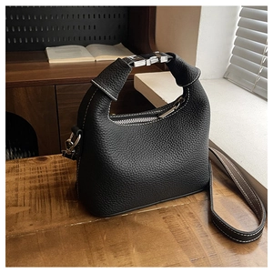 Close-up of black lychee leather bag with white stitching and silver metal buckle