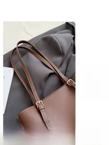 Dettaglio dei cinturini regolabili in pelle marrone con fibbie dorate della borsa