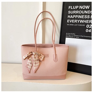 Detailed close-up of a pink woven tote bag featuring an elegant ribbon scarf decoration