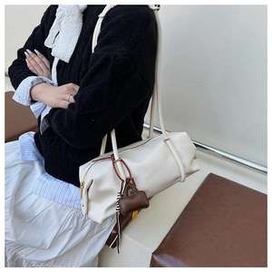 Detail of white leather barrel bag with litchi grain and decorative mini charm
