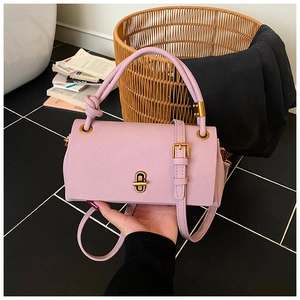 Detail of lilac pebbled leather handbag with gold twist lock and braided handle knot