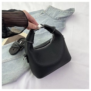 Detail of black lychee grain leather handbag with white contrast stitching and silver zipper