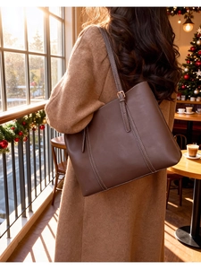 Dettaglio di una borsa tote in pelle marrone con cuciture bianche e fibbia regolabile
