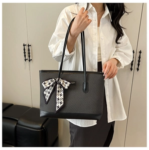 Detail of grey checkered tote bag with black leather panels and houndstooth bow accent