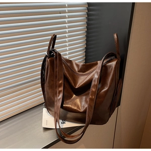 Close-up of a large dark brown leather tote bag showing side zipper pocket details