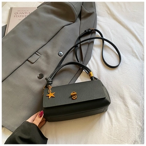 Detail of black pebbled leather bag with gold star pendant and metallic twist lock clasp