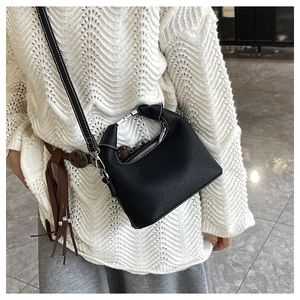 Detail of black lychee grain leather bag with white contrast stitching and silver hardware