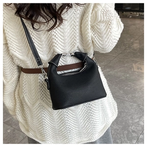 Detail of black lychee grain leather handbag with silver metal handle and shoulder strap