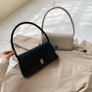 Detail of minimalist black and beige baguette bags with gold metal clasps on trench coat