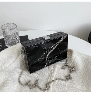 Detail of black marble acrylic clutch bag with silver chain and elegant square push-lock