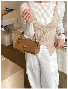 Detail of a brown structured handbag with a gold star charm and knotted handle design