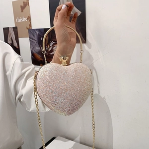 Detailed view of heart-shaped glitter evening clutch with gemstone clasp and gold chain