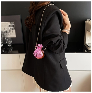 Detail of metallic pink drawstring mini bag with gold chain strap on a black blazer