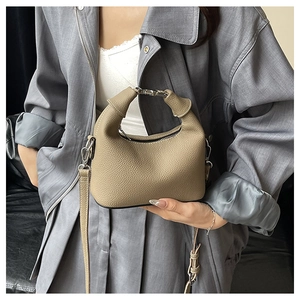 Close-up of khaki pebbled leather handbag with gold metal handle and long strap