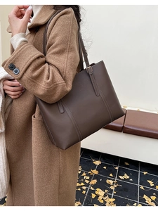 Dettaglio della borsa tote marrone scuro con cuciture bianche a contrasto e fibbia in metallo