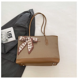 Detailed view of tote bag with brown fabric texture, leather trim and houndstooth scarf