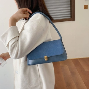 Detail of blue patchwork shoulder bag with gold metal buckle shown on a model