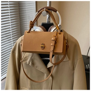 Detailed close-up of a tan leather crossbody bag with a distinctive golden metal buckle
