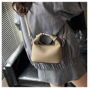 Detail of khaki lychee grain leather mini bag with silver metal handle and shoulder strap