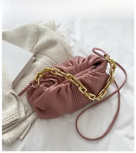 Detail of dusty pink ruched cloud bag featuring thick gold chain and leather strap