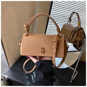 Detail of brown leather handbag with knot handle design and metallic gold buckle finish