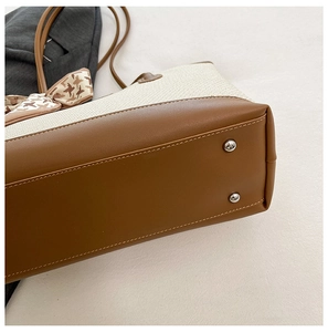 Close-up of tote bag bottom featuring protective metal feet and woven texture