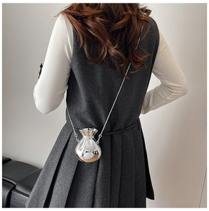 Detailed view of a silver metallic drawstring mini bag with a fine chain strap on a model