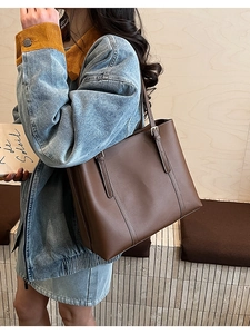 Dettaglio della borsa tote in pelle marrone scuro con cuciture fini e fibbie in metallo