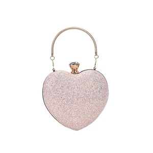 Detail of a pink sequin heart clutch bag with a gold metal handle and rhinestone clasp