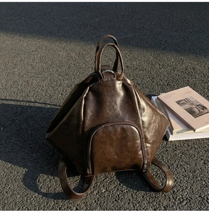 Detail view of dark brown PU leather backpack with geometric shape on asphalt background