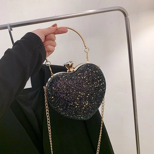 Detail of heart-shaped evening bag with black glitter and gold circular metal handle