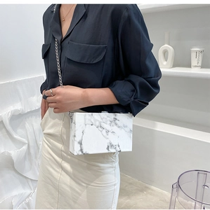 Close-up of marble texture hard shell box bag with silver metal chain and lock
