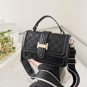 Detail of black crossbody bag with checkered texture and wide striped woven strap