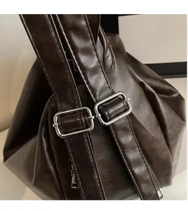 Detail of dark coffee PU leather backpack with adjustable straps and silver metal buckles