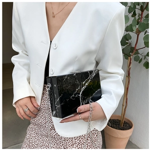 Detail of a square marble texture box bag with silver metal chain on a model