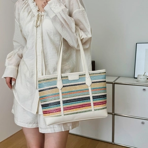 Colorful striped woven straw tote bag with white leather straps and a casual style
