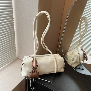 Minimalist beige cylindrical shoulder bag with premium litchi grain texture and hanging charm