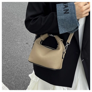 Detail of khaki pebbled leather mini bag with unique knotted handle and thin shoulder strap