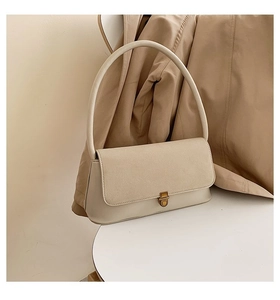 Detail of beige vintage underarm bag featuring suede patchwork and gold metal clasp