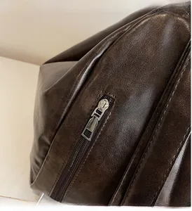 Close-up of smooth silver zipper and fine stitching on dark brown leather backpack