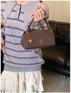 Detail of coffee brown lychee leather handbag with gold twist lock and star pendant