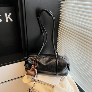 Glossy black Boston bag with heart charm against minimalist modern home decor